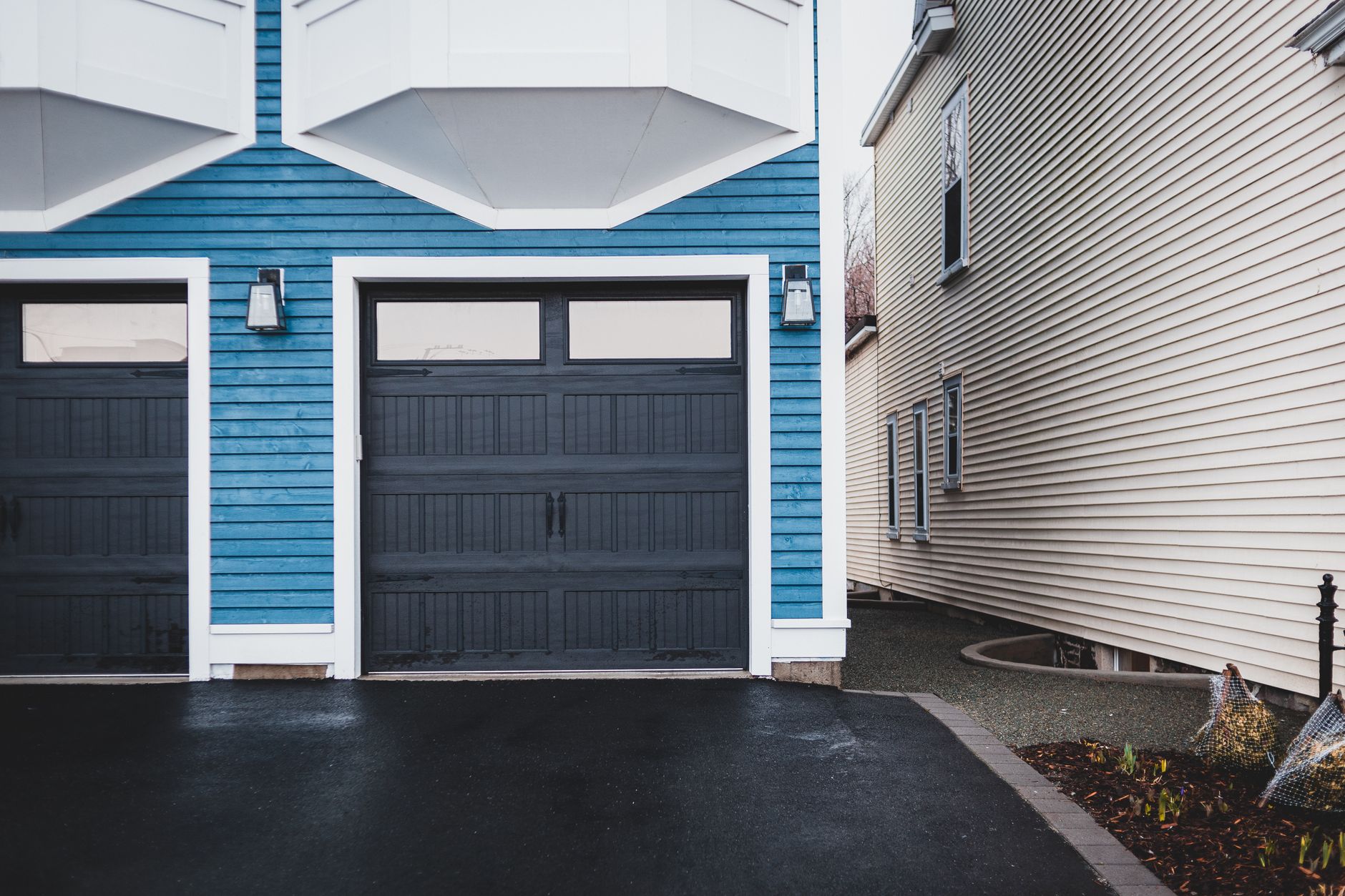 side-by-side before and after of a concrete driveway, half dark with grime and half bright clean