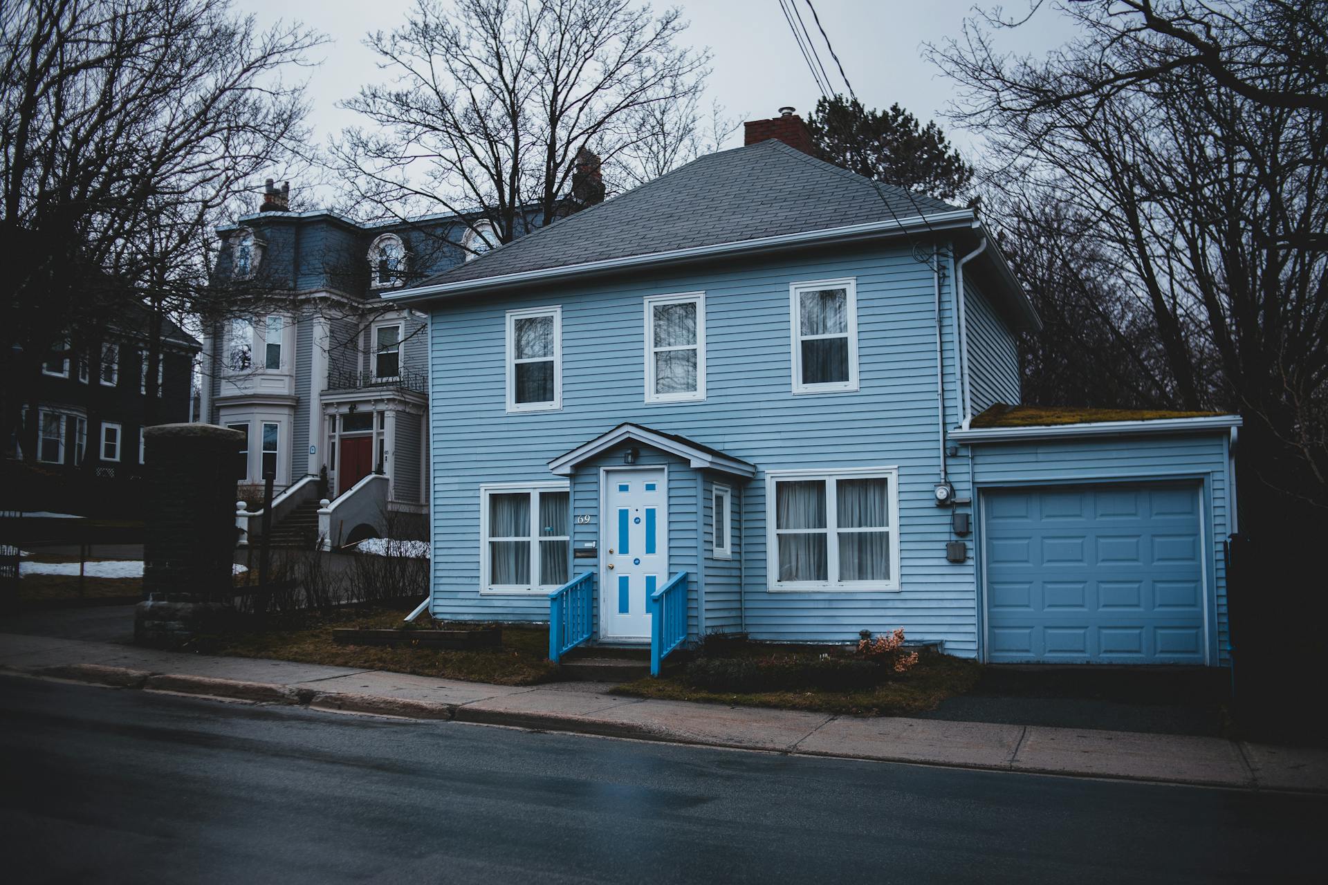 A cozy blue house with garage in a suburban neighborhood, showcasing quaint architectural style.