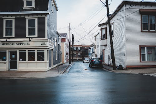 Facade of residential houses and wet asphalt road located on street of city