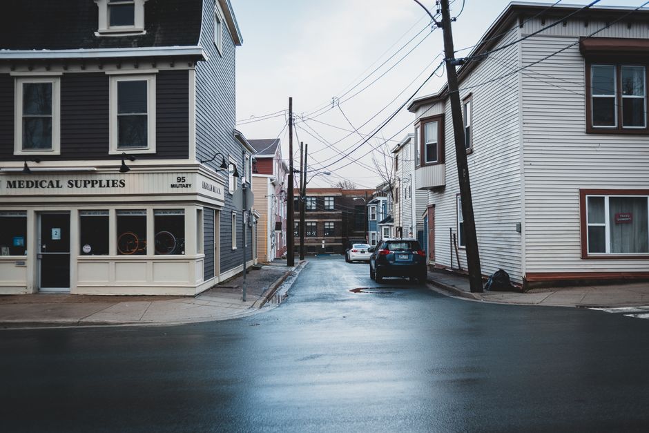 Facade of residential houses and wet asphalt road located on street of city