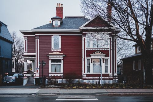 Free Exterior of aged residential house of white and red colors and pavement with leafless trees on street Stock Photo