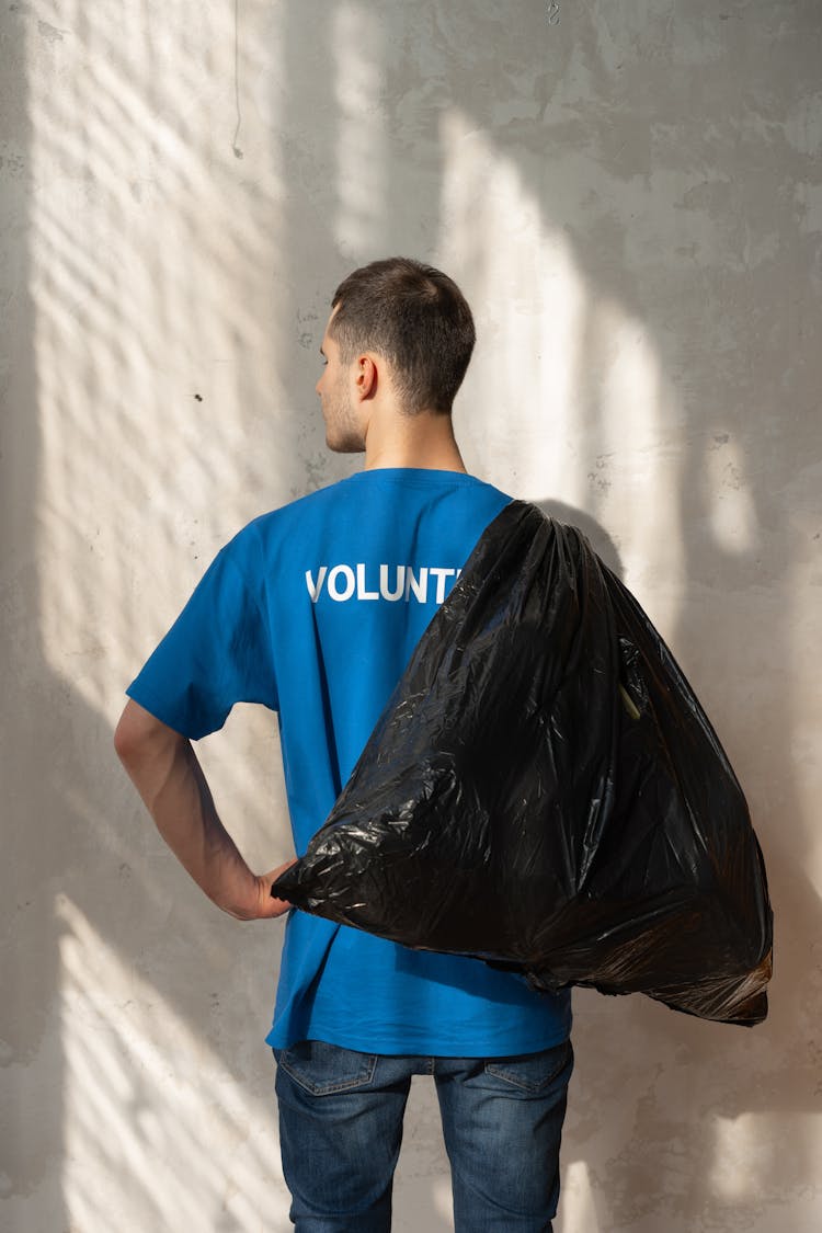 Back View Of A Man Holding A Black Garbage Bag 