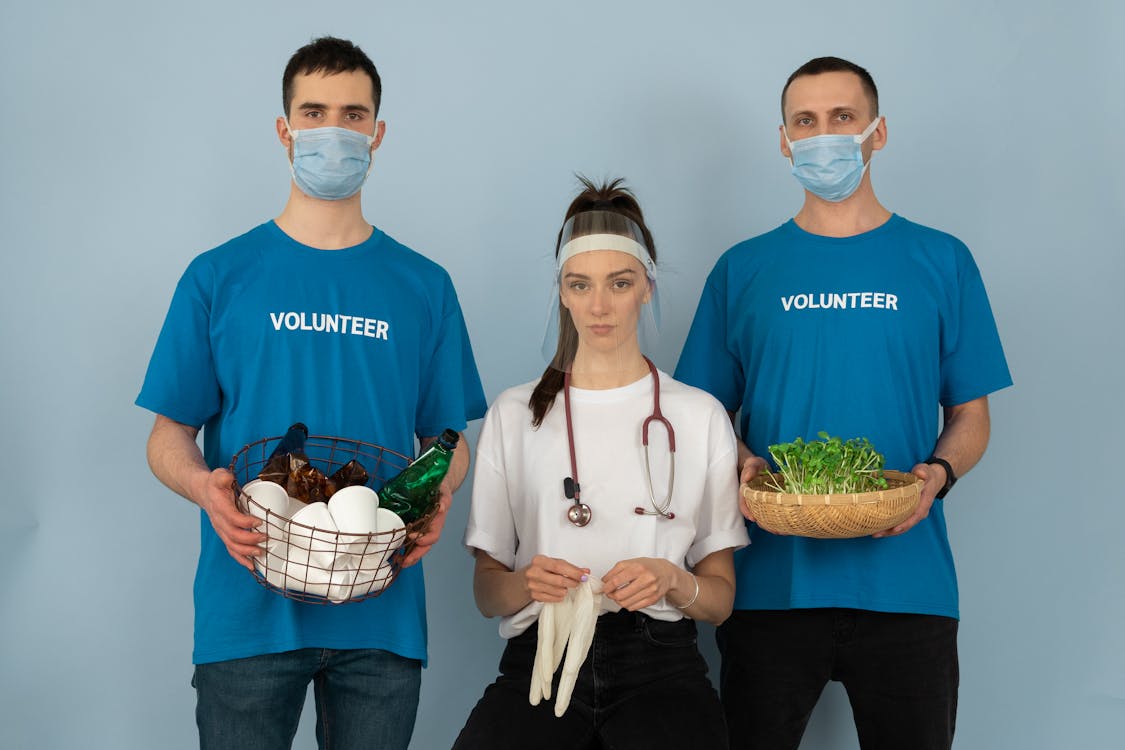 Free Woman in Blue Crew Neck T-shirt Holding White and Green Flowers Stock Photo