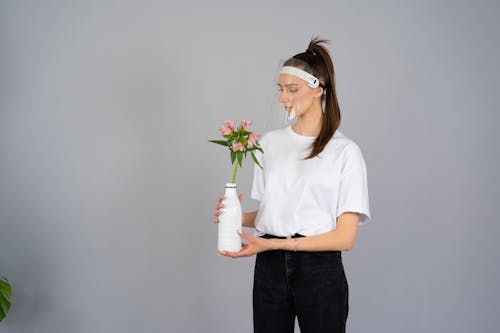 Woman in White Crew Neck T-shirt Holding Pink Flower