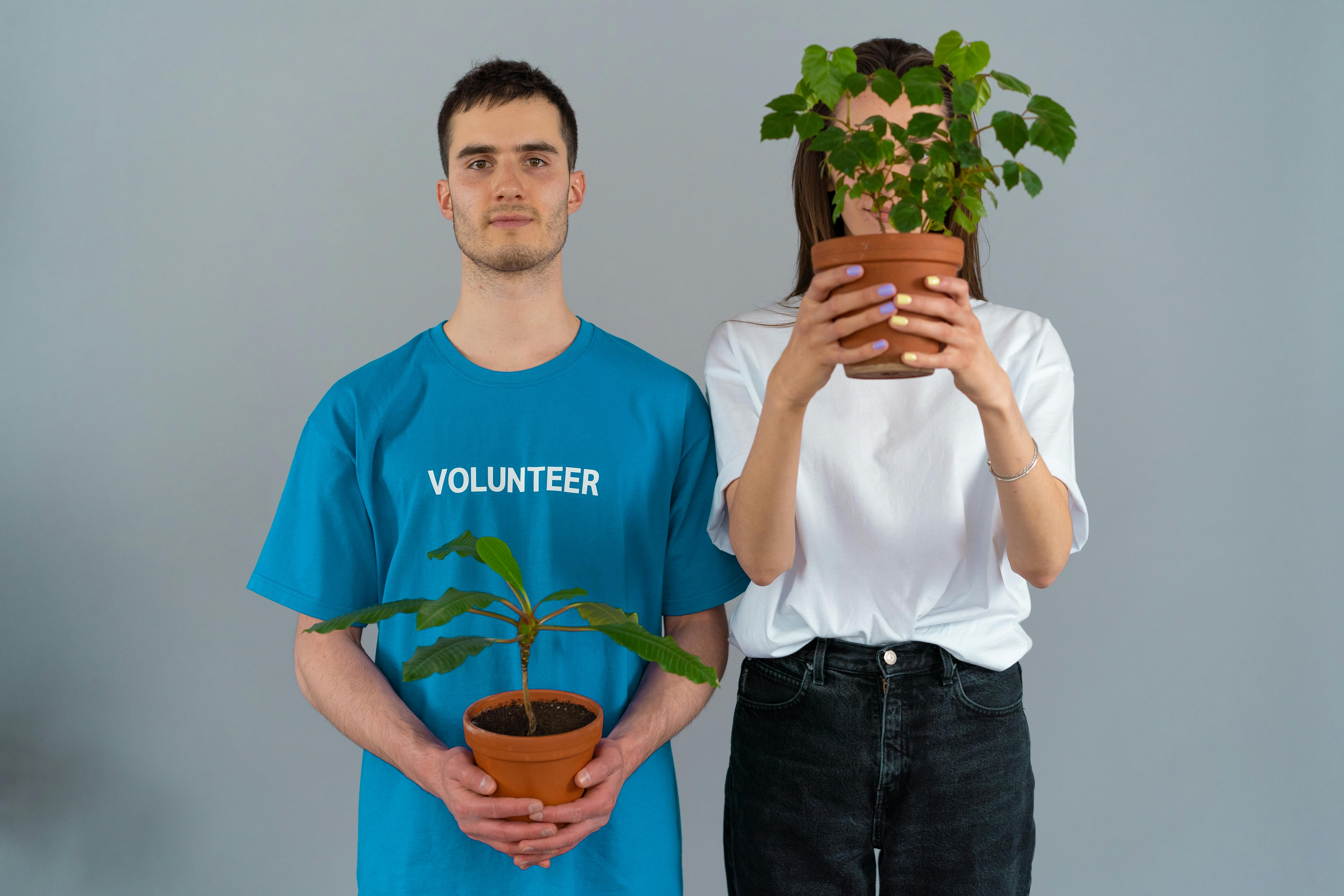 man in blue crew neck t shirt holding brown pot with green plant