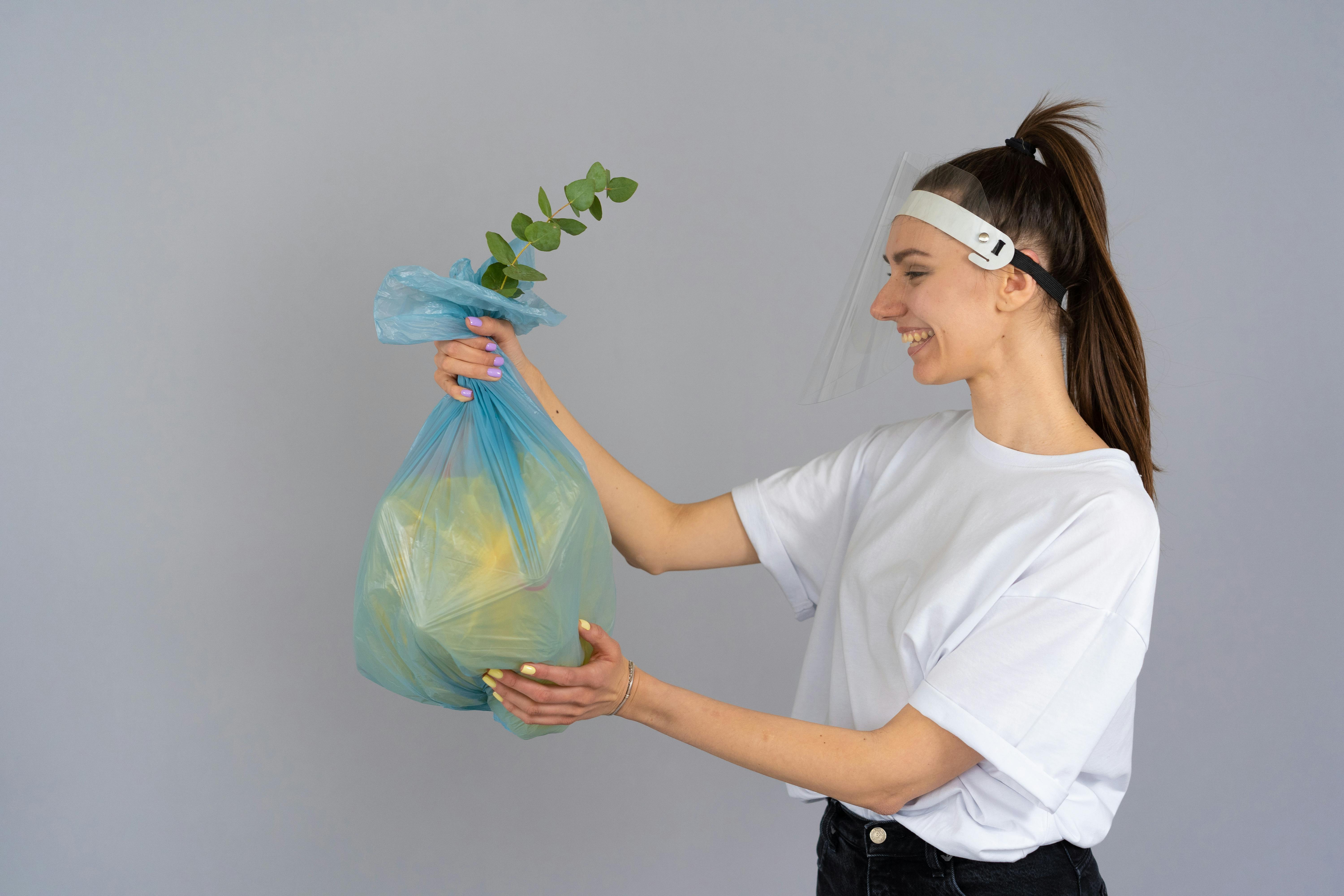 woman in white crew neck t shirt holding green plastic bag