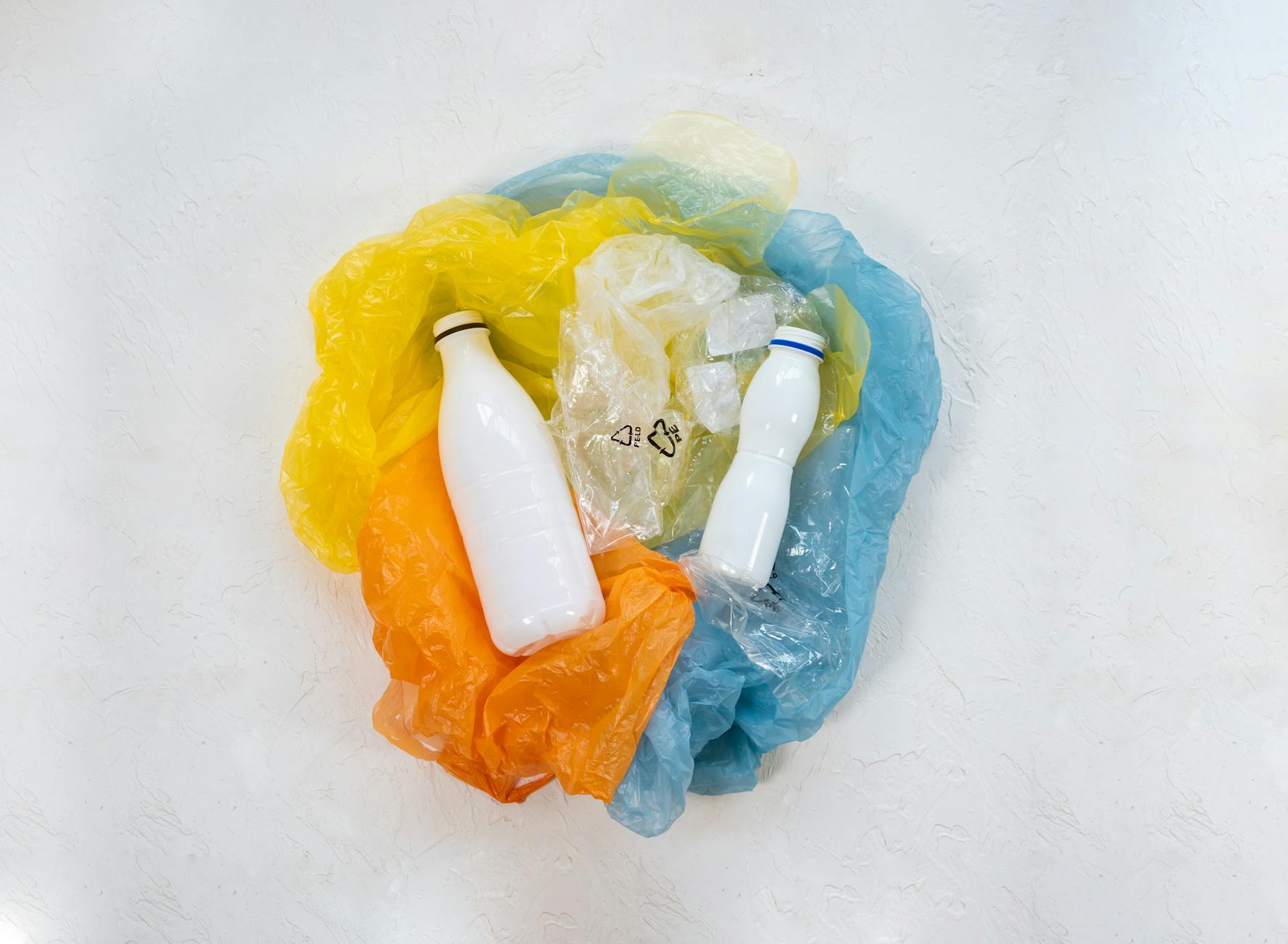 Plastic bottles surrounded by colourful plastic bags symbolising recycling and pollution issues.