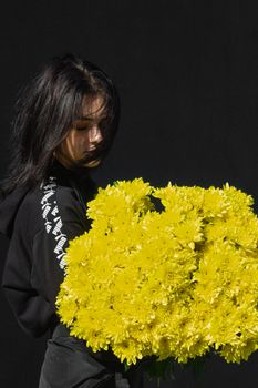 Woman holding a vibrant yellow chrysanthemum bouquet against a dark background. - Fotografer Sidoarjo