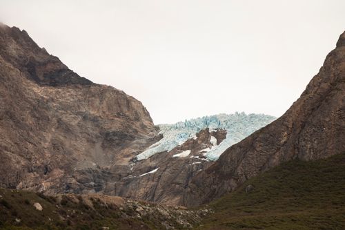 Free Breathtaking view of a glacier nestled between rugged rocky mountains, showcasing nature's raw beauty. Stock Photo