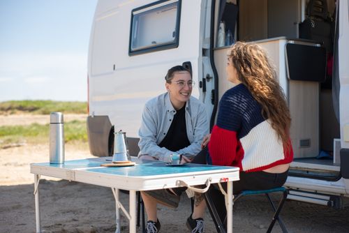 Free Two people having a cheerful moment by their RV, enjoying a sunny day at a campsite. Stock Photo