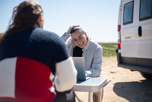 Free Two people enjoying remote work near a van in a sunny outdoor setting in Portugal. Stock Photo
