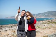Woman in White Jacket and Woman in Red Knit Sweater Standing on Beach
