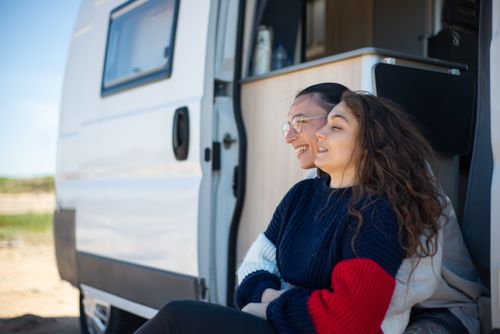 Free Happy couple relaxing by a camper van on a sunny day in Portugal, enjoying travel and togetherness. Stock Photo