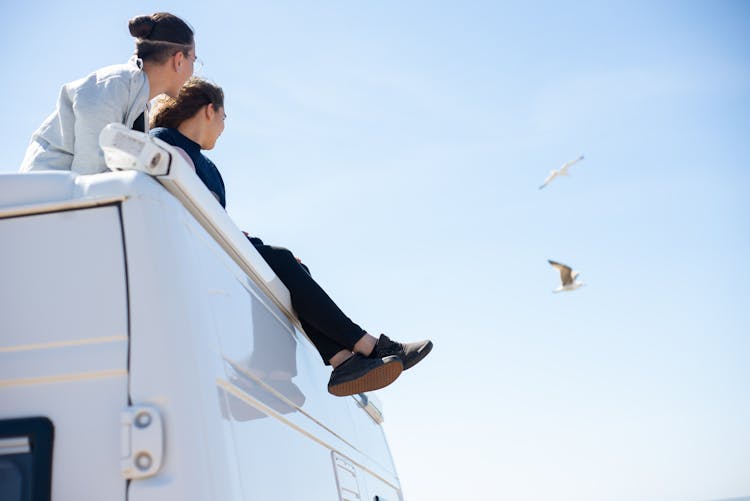 A Couple Sitting On Top Of An RV