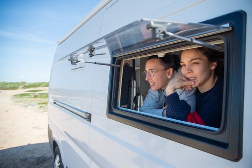 Free Lesbian couple relaxing in a camper van, embracing freedom and outdoor adventure. Stock Photo