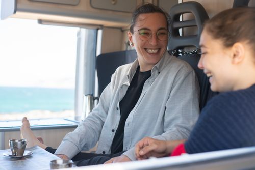 Free Happy couple relaxing in a van by the beach, enjoying a cheerful moment together. Stock Photo