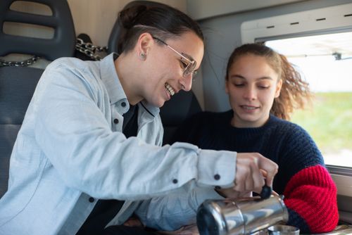 Free A joyful couple pours coffee in a motorhome, capturing a cozy travel moment. Stock Photo
