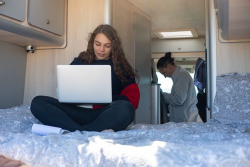 Free Young woman focused on using a laptop inside a camper van, enjoying a mobile lifestyle. Stock Photo