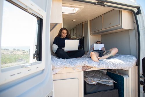 Free A couple enjoys a relaxing day in their motorhome, one using a laptop and the other reading a book. Stock Photo