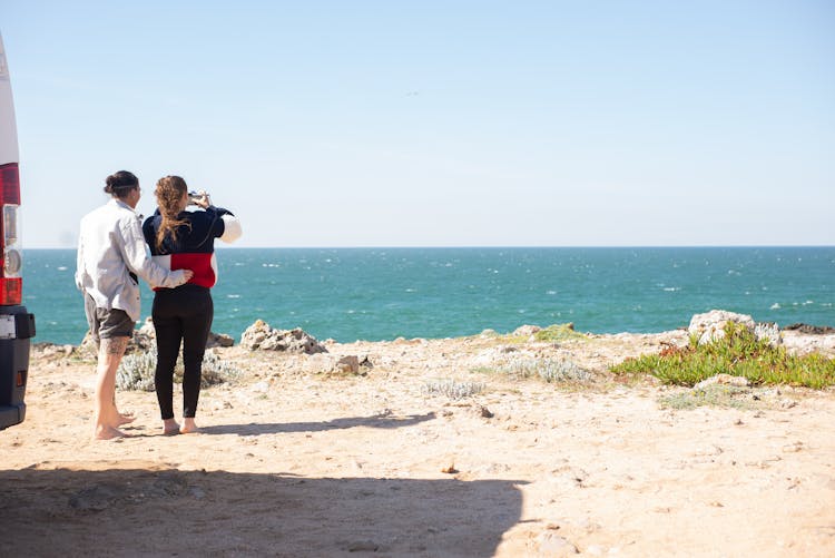 Couple Standing On The Beach And Taking Pictures 