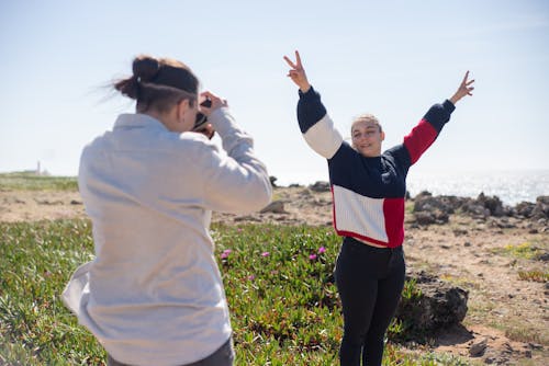 Free Woman in a Sweater Doing the Peace Sign with Her Hands Stock Photo