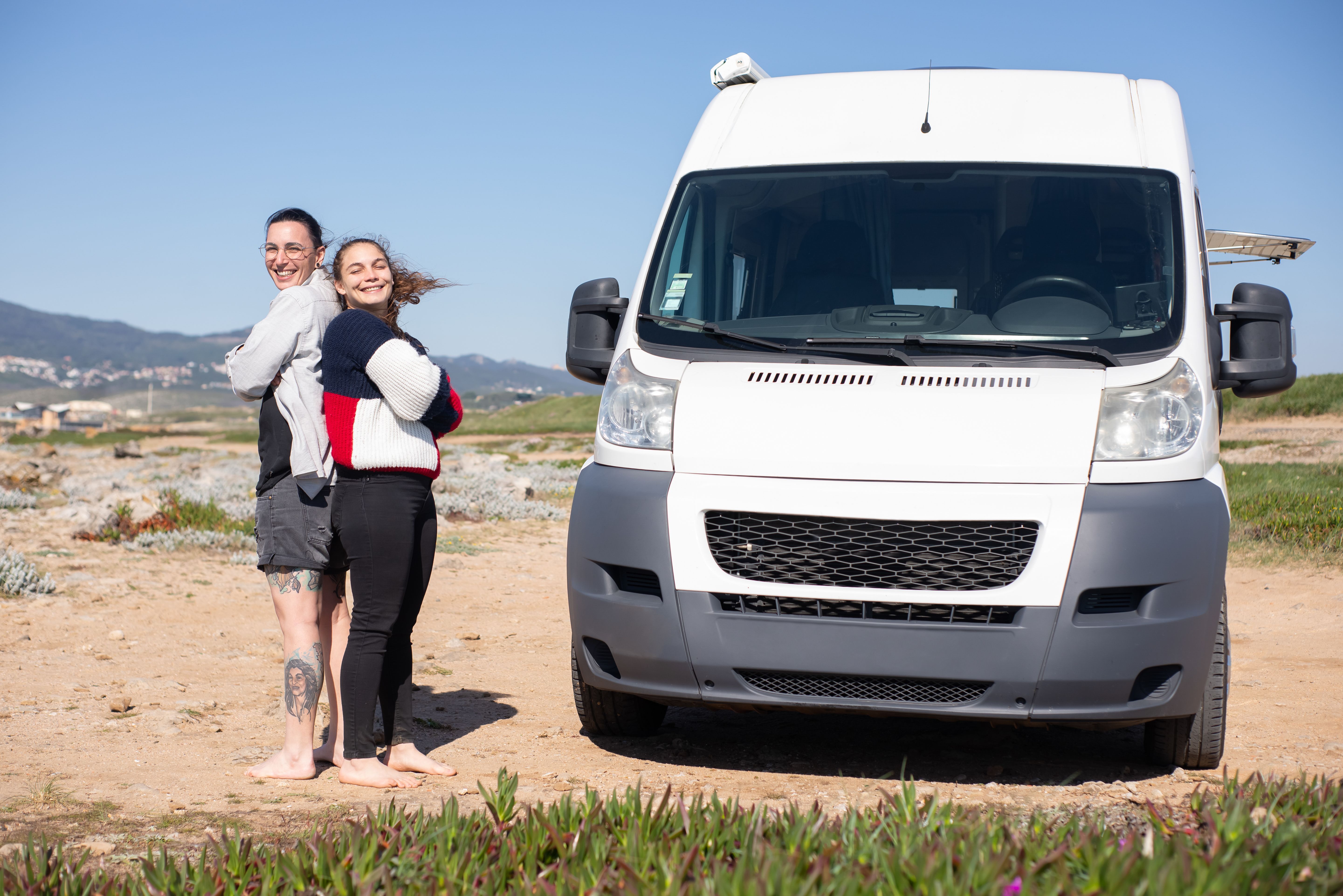 two backpackers loading a campervan on an Australian beach