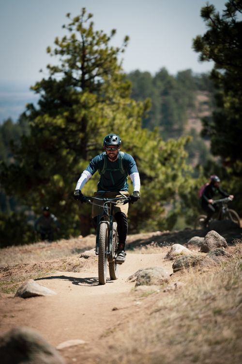 Free A group of cyclists enjoying an exhilarating mountain biking trail in a forest setting. Stock Photo
