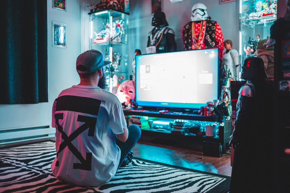 A young man sitting on a rug, immersed in gaming in a sci-fi themed room.