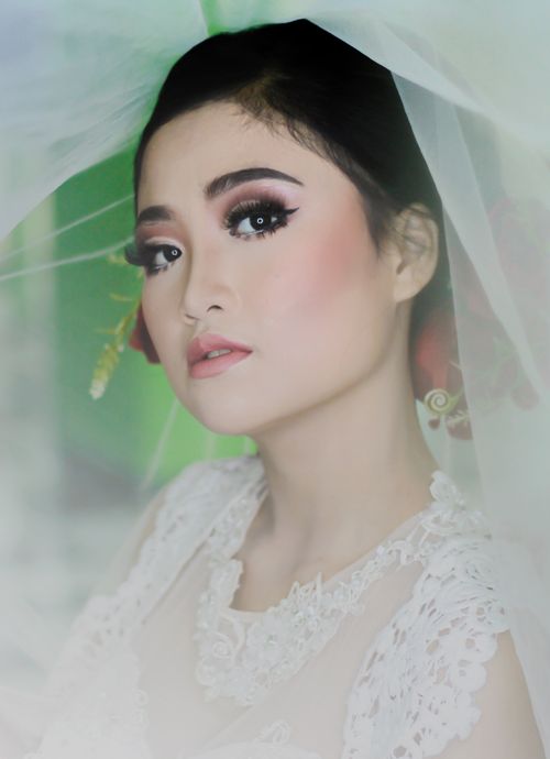 Free Close-up portrait of an elegant bride in a lace gown with intricate makeup and veil. Stock Photo