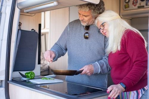 Free Senior couple cooking together in a motorhome kitchen during a travel trip in Portugal. Stock Photo