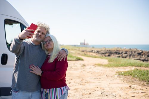 Free A happy senior couple takes a selfie near their motorhome on a sunny coastal day in Portugal. Stock Photo