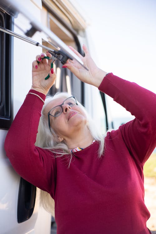 Elderly Woman Fixing a Window in a Campervan