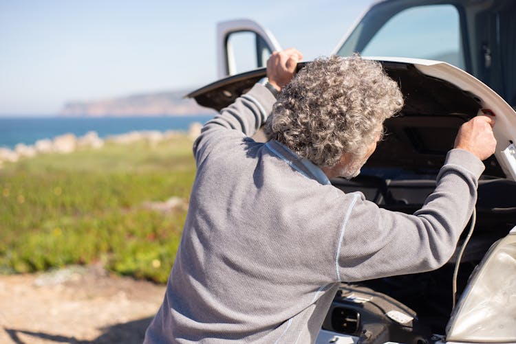 Back View Of Man Holding The Hood Of A Car 