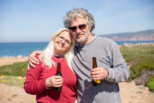 Close-Up Shot of a Couple Holding Bottles of Alcoholic Drinks