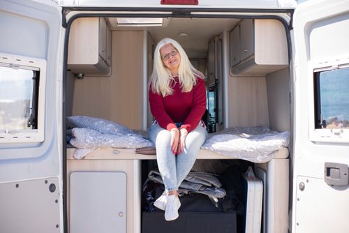 Free Elderly woman with blonde hair sitting happily in a campervan during a roadtrip in Portugal. Stock Photo