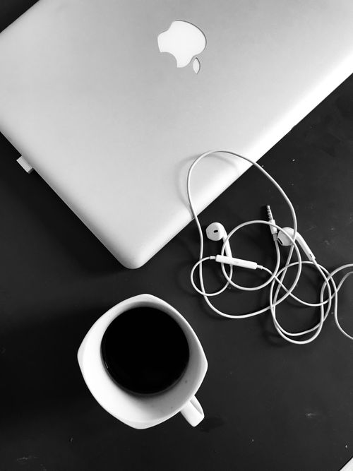 Free Top view of a minimalist workspace featuring a laptop, coffee cup, and earphones. Stock Photo