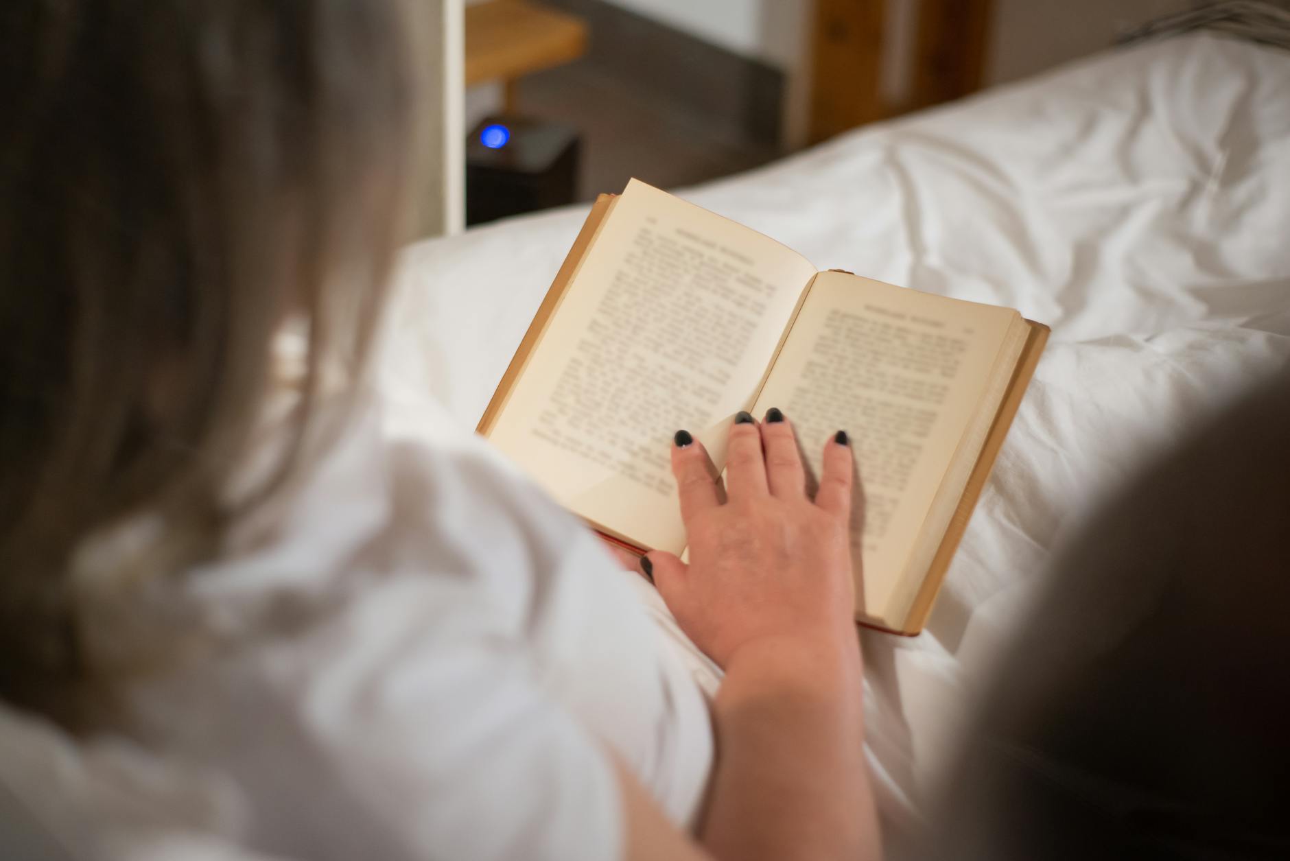 A woman engrossed in reading a book while relaxing indoors in a cozy setting.