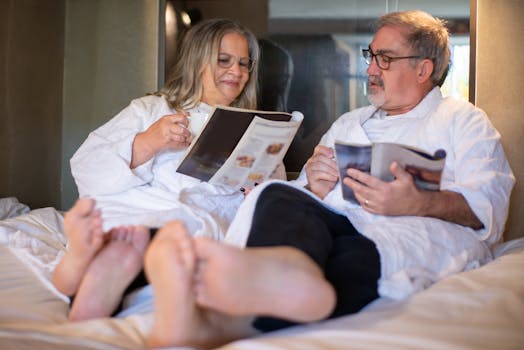 Elderly couple enjoys a relaxing morning reading magazines in bed.