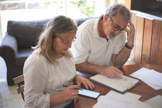 Elderly couple reviewing bills and documents at home, focusing on finances and technology.