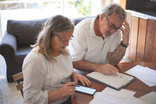 Free Elderly couple reviewing bills and documents at home, focusing on finances and technology. Stock Photo