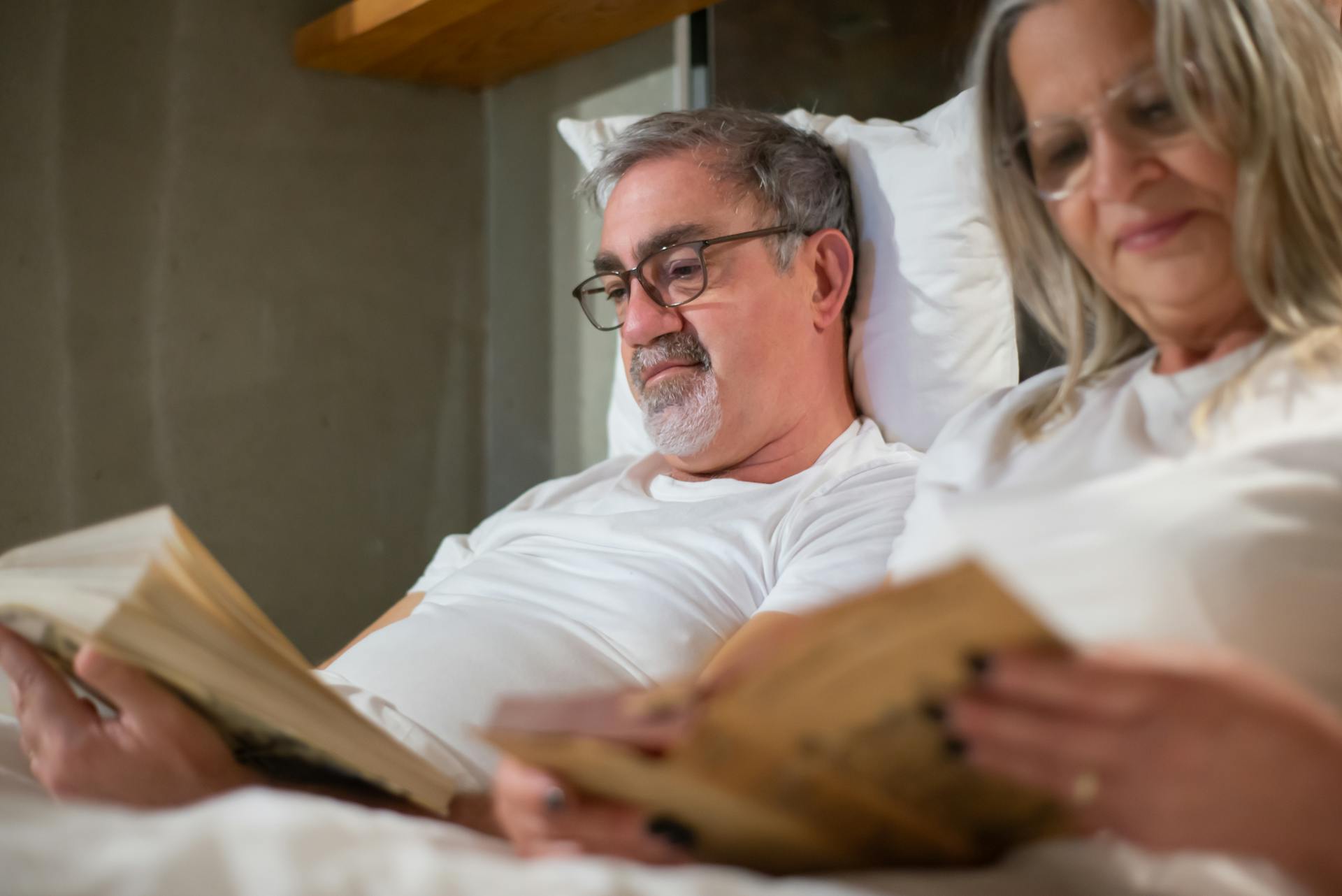 Elderly couple enjoying leisure reading in a cozy indoor setting. Perfect portrayal of retirement lifestyle.