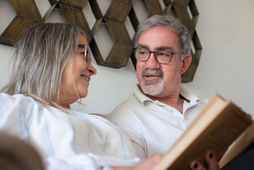 Free Senior couple enjoying a peaceful moment reading together indoors. Warm and loving atmosphere. Stock Photo