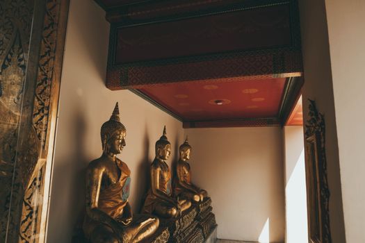 Golden Buddha statues inside a Bangkok temple, showcasing traditional Thai architecture.