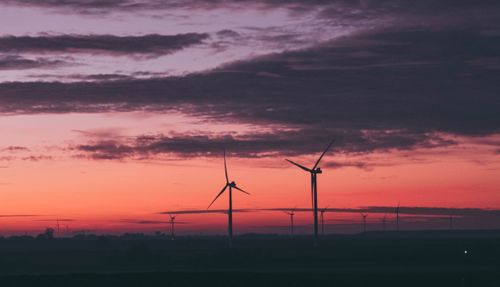 Free Silhouettes of wind turbines against a vibrant sunset sky in Belgium, showcasing renewable energy. Stock Photo