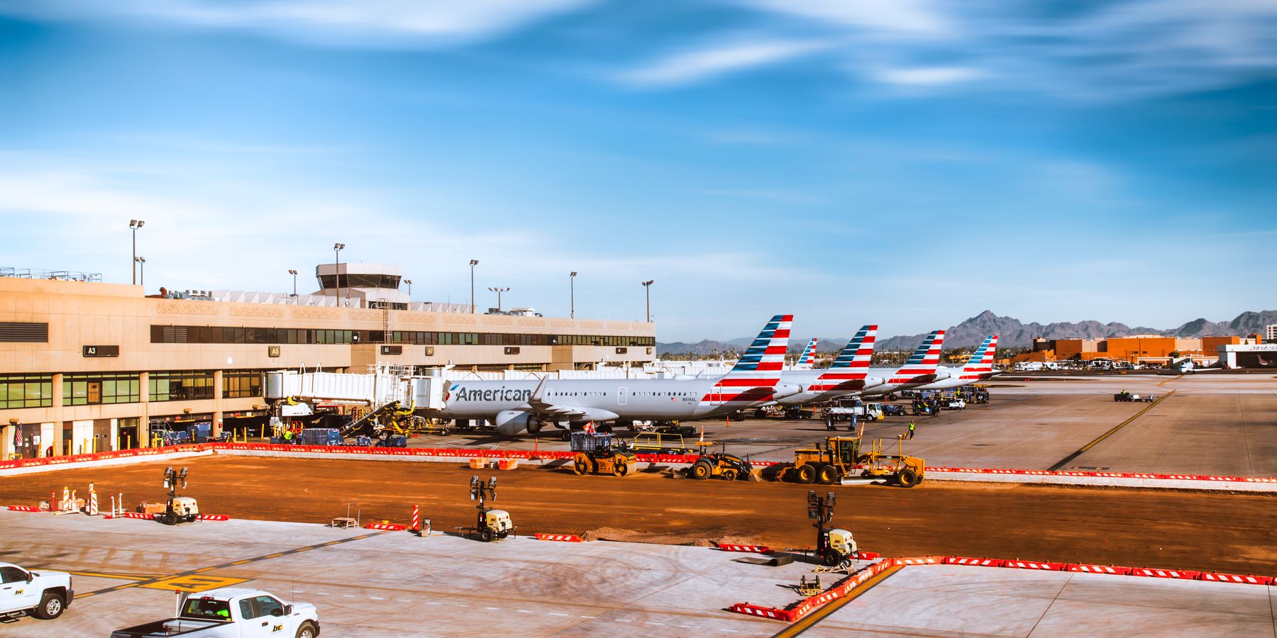 Line of American Airlines planes at Phoenix Sky Harbor with mountains in background.