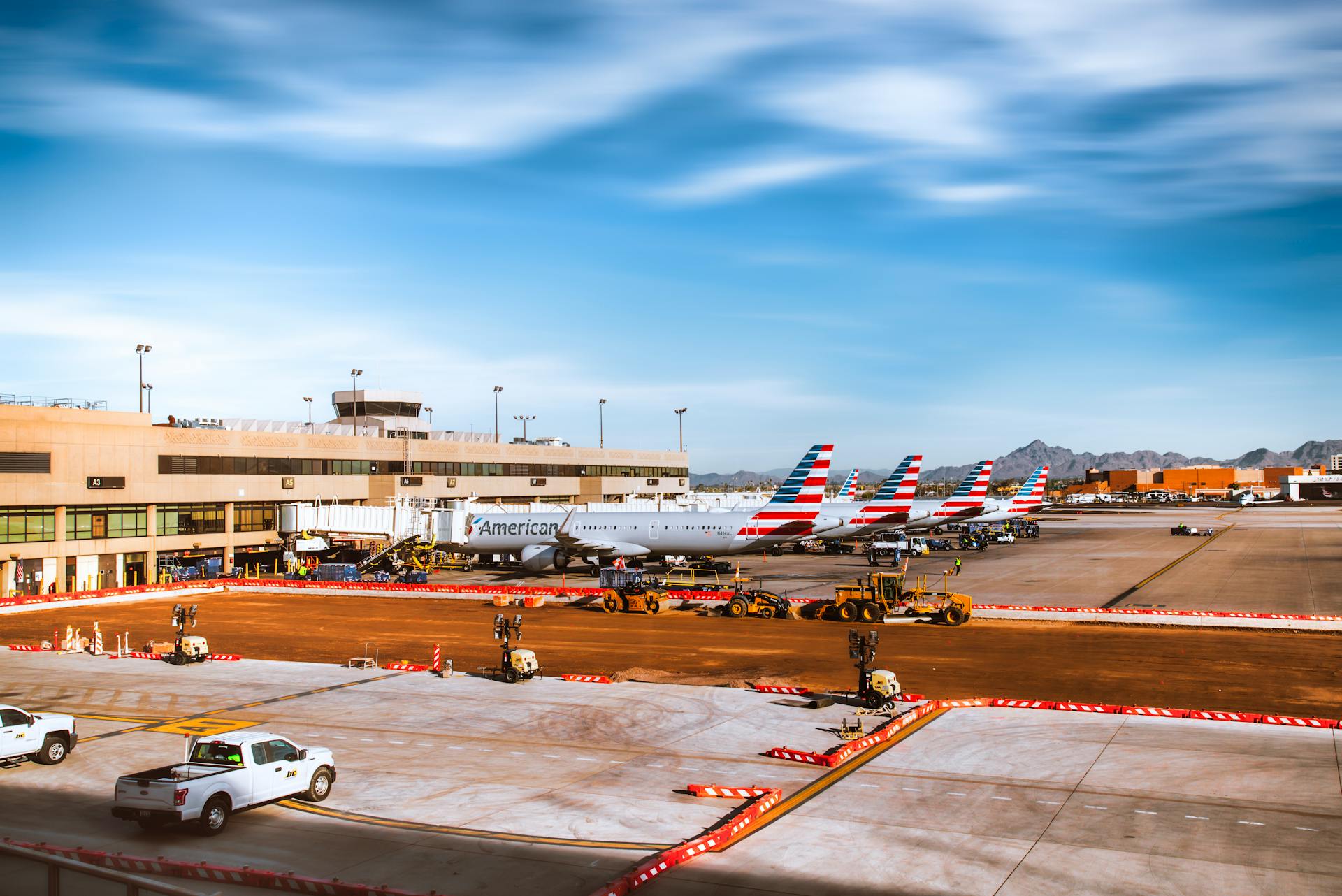 Line of American Airlines planes at Phoenix Sky Harbor with mountains in background.