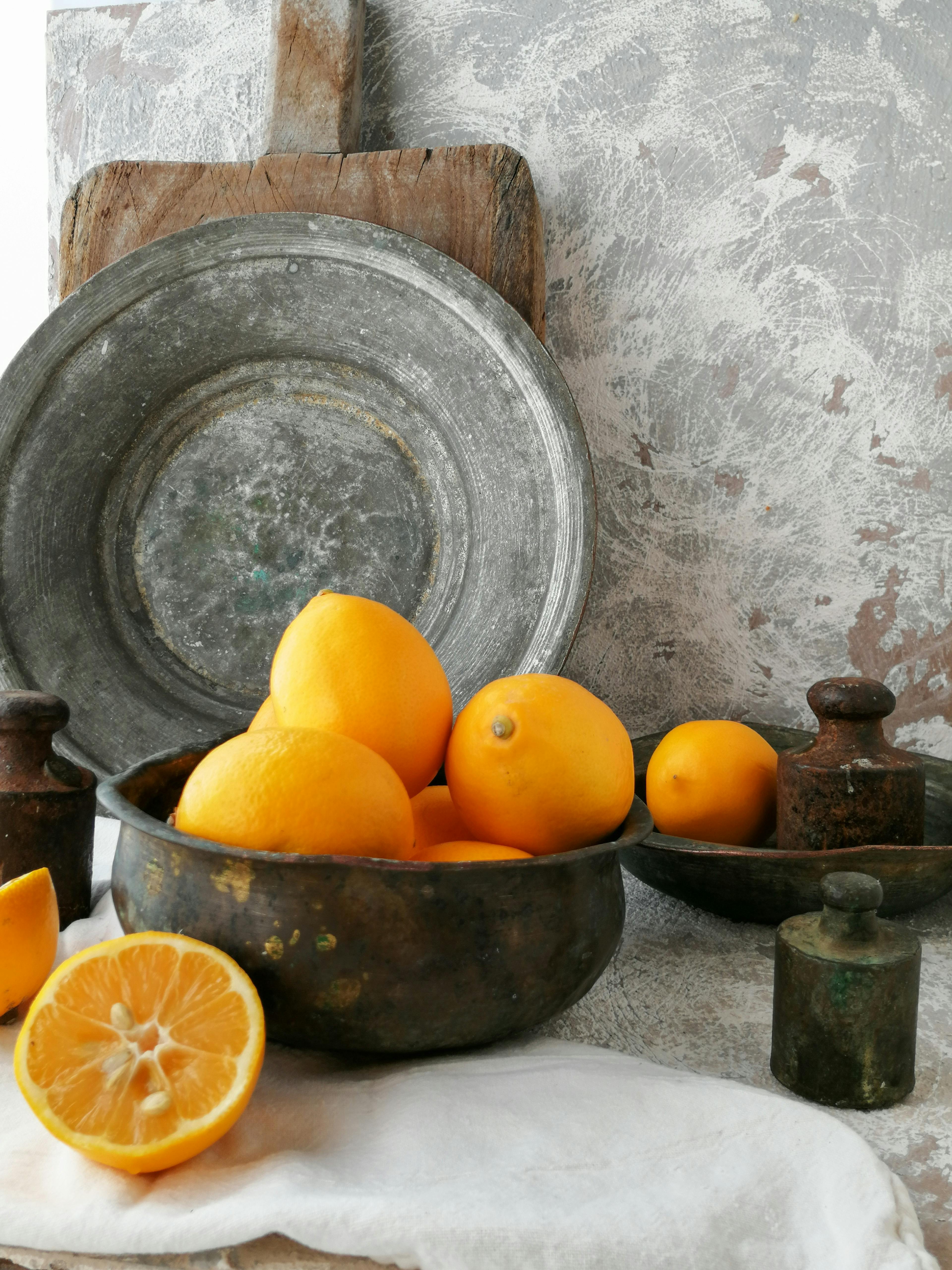 Vintage still life featuring fresh lemons in a rustic setting with a copper bowl.