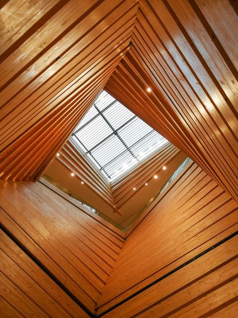 Contemporary interior with geometric wooden architecture and skylight feature.
