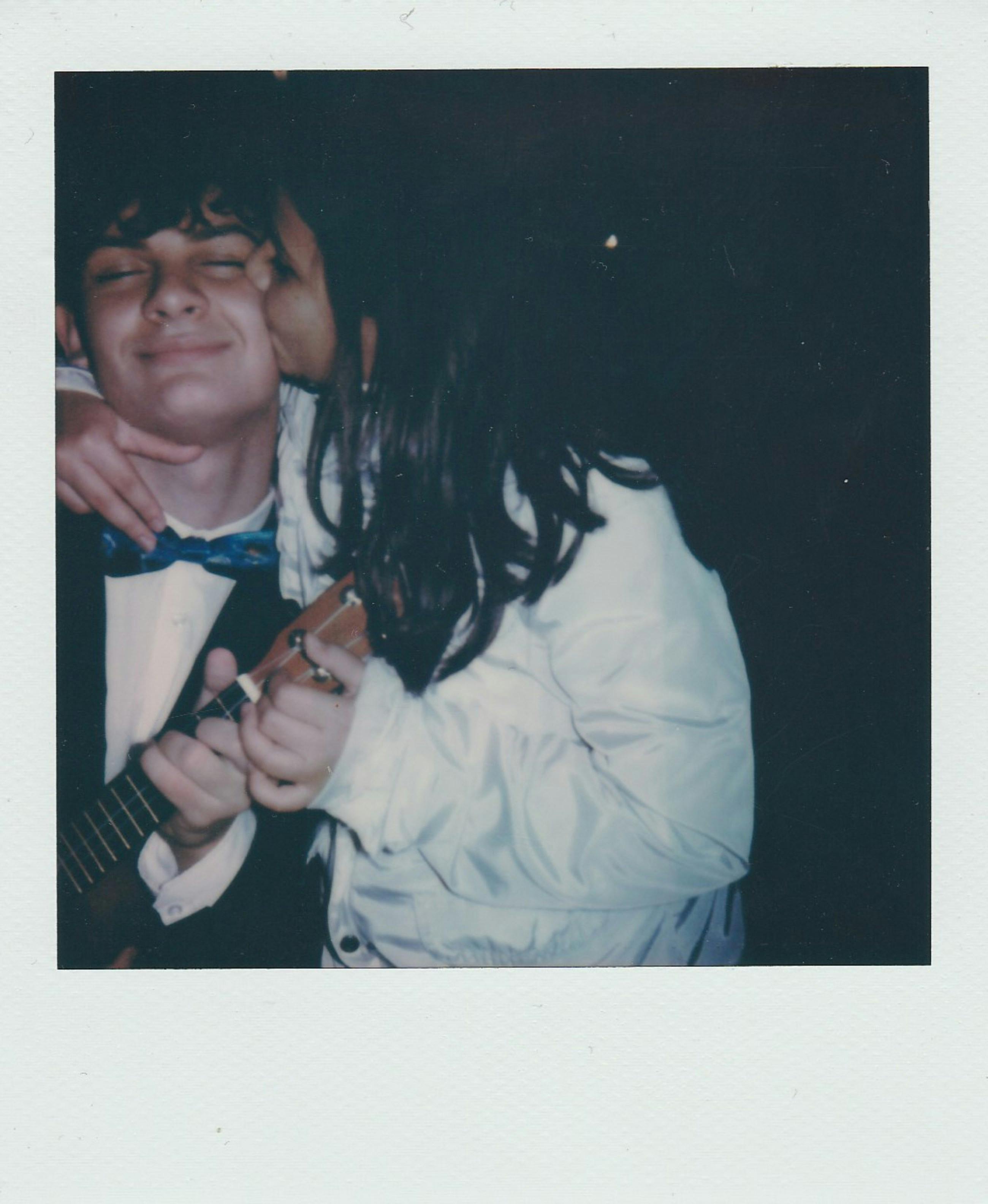 Young couple shares a romantic moment with a Polaroid photo backdrop.