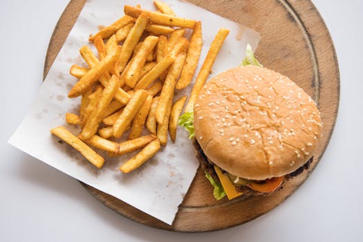Delicious cheeseburger served with crispy french fries on a wooden tray. Perfect for fast food lovers.